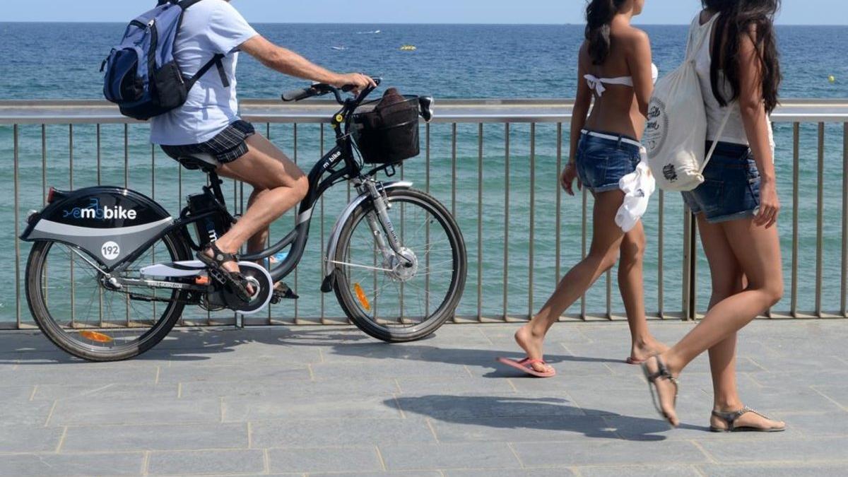Un turista con una bicicleta eléctrica, en el paseo Marítimo de la Barceloneta