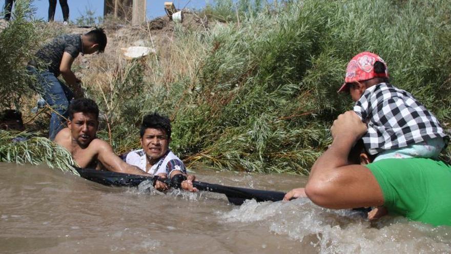 Varios migrantes tratan de cruzar un río en México.