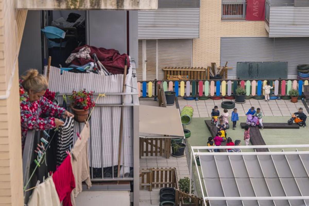 Una mujer tiende la ropa con los alumnos de la guardería municipal La casa de les flors de L'Hospitalet de fondo.
