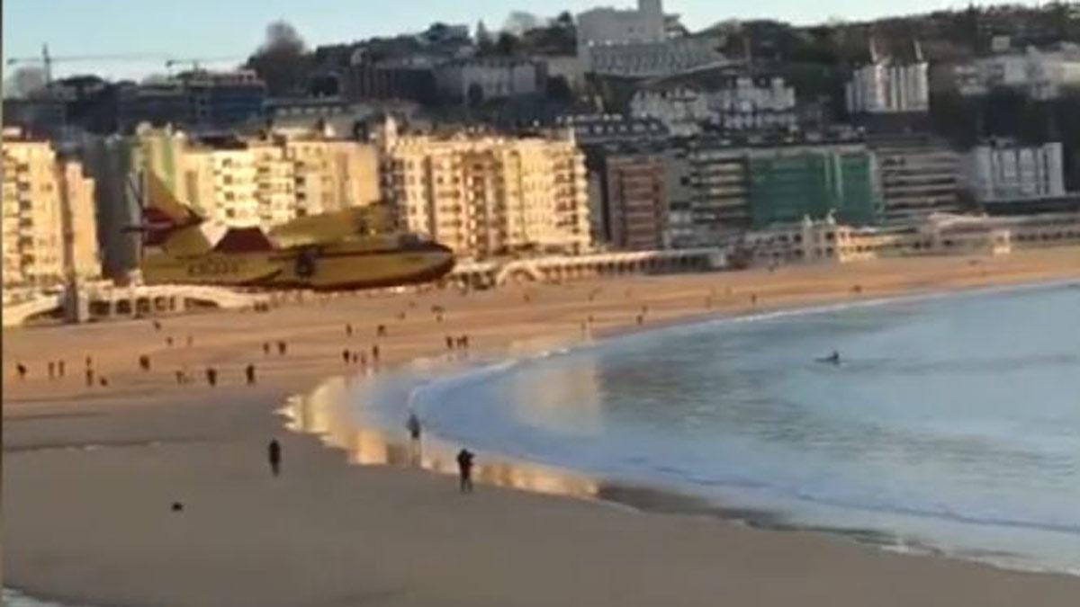 Un hidroavión vuela muy bajo sobre la playa de la Concha para recoger agua