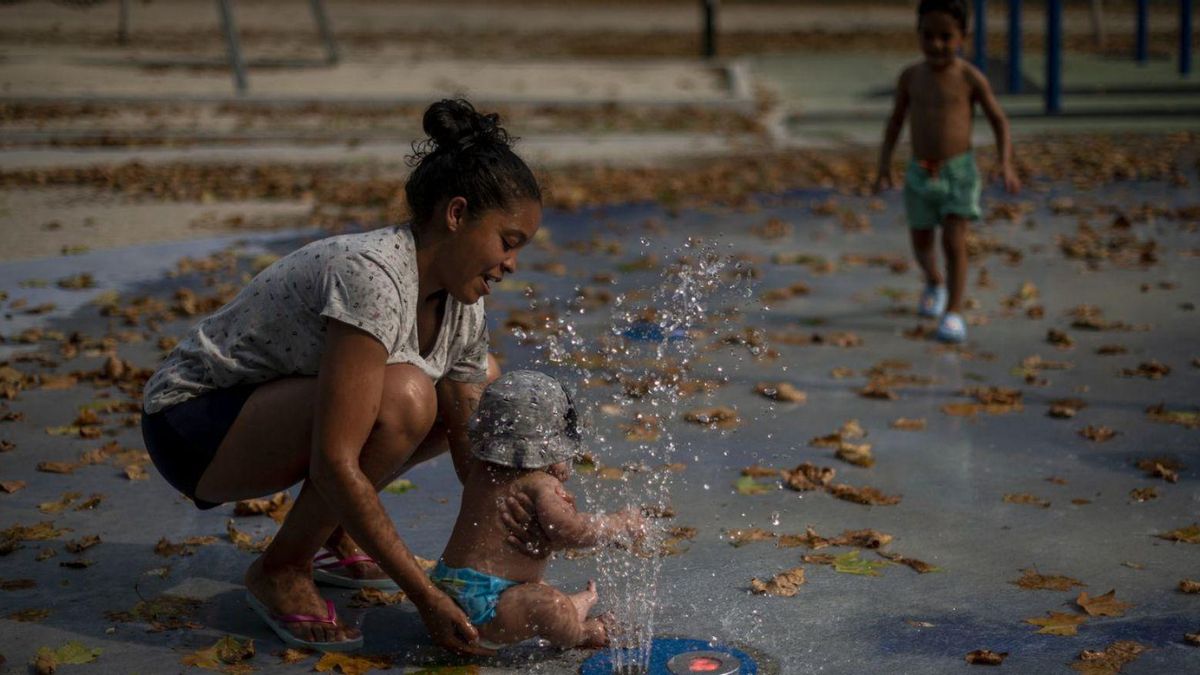 Una mujer con un bebé, refrescándose en estos días de extremo calor.