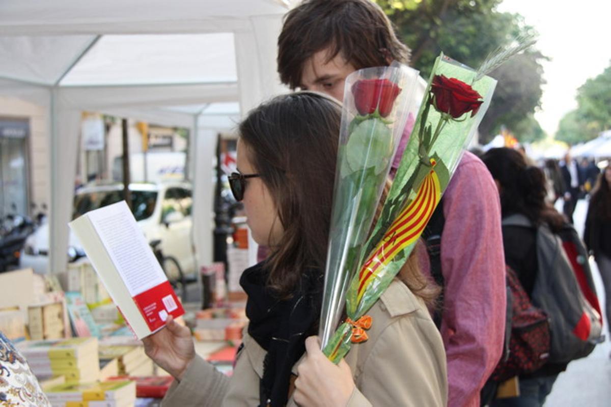 Una pareja compra las primeras rosas y libros en la diada de Sant Jordi 2014.