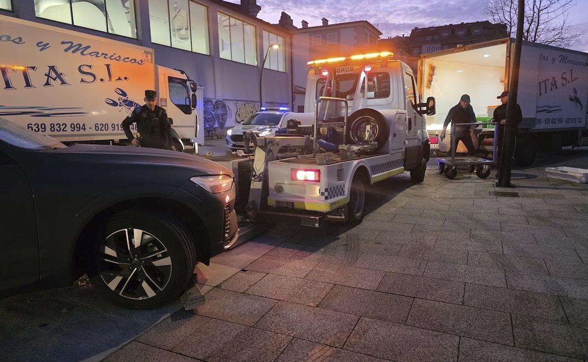 La policía y la grúa llevándose un coche de la zona del mercadillo y la plaza, esta mañana.