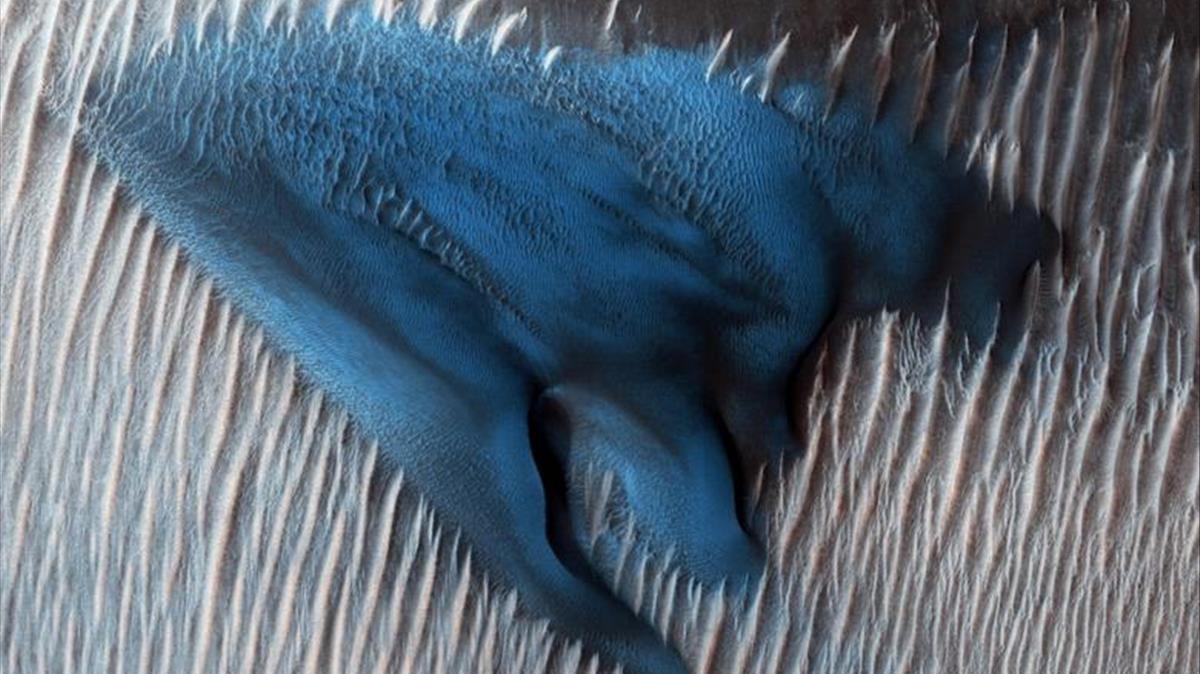 Un campo de dunas de arena barchan aparece de color azul turquesa en la superficie de Marte en esta imagen mejorada tomada por el Mars Reconnaissance Orbiter