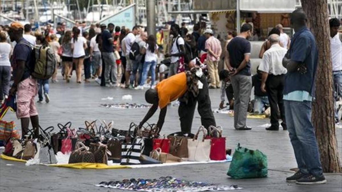 Un vendedor prepara su mercancía de bolsos falsificados ante el Maremágnum, este sábado.