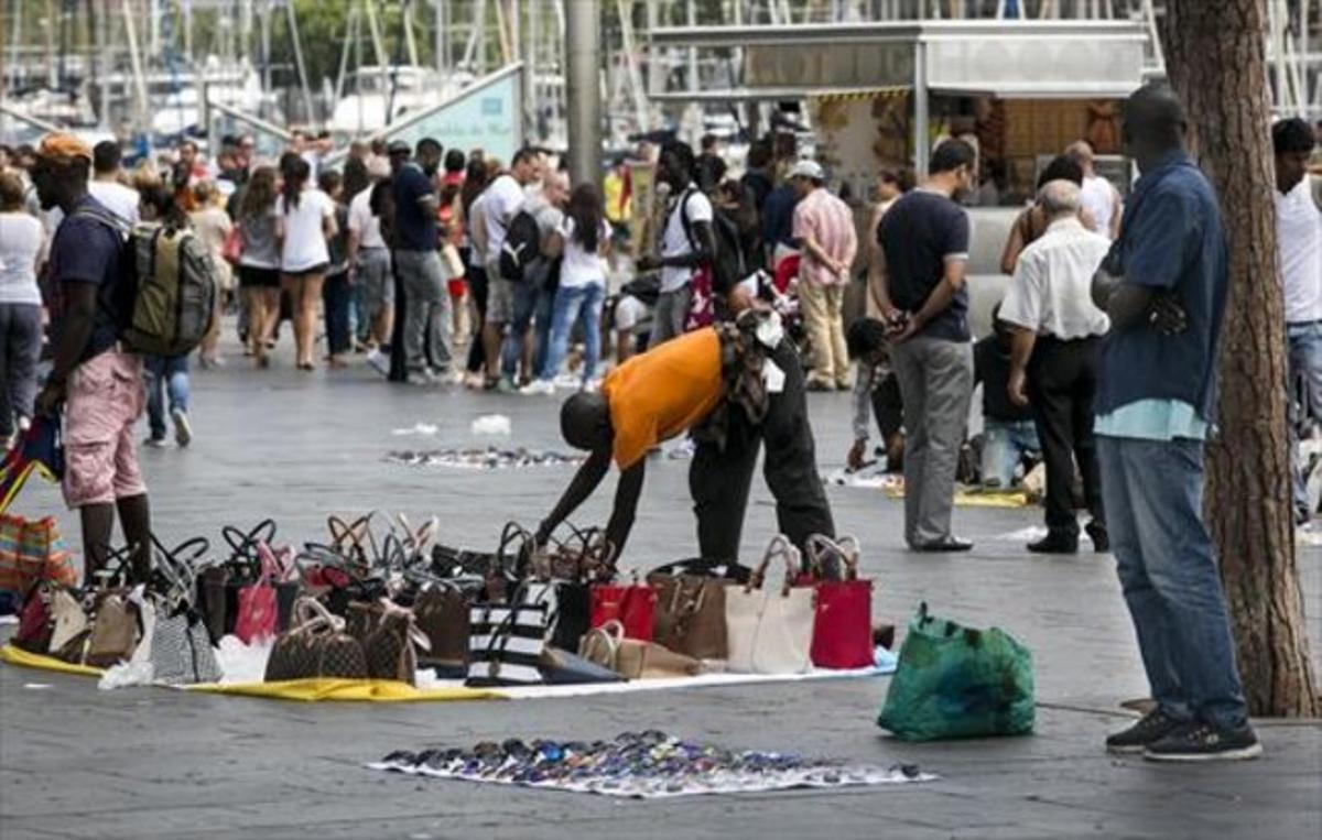Un venedor prepara la seva mercaderia de bosses falsificades davant el Maremàgnum, dissabte. Un venedor prepara la seva mercaderia de bosses falsificades davant el Maremàgnum, dissabte.