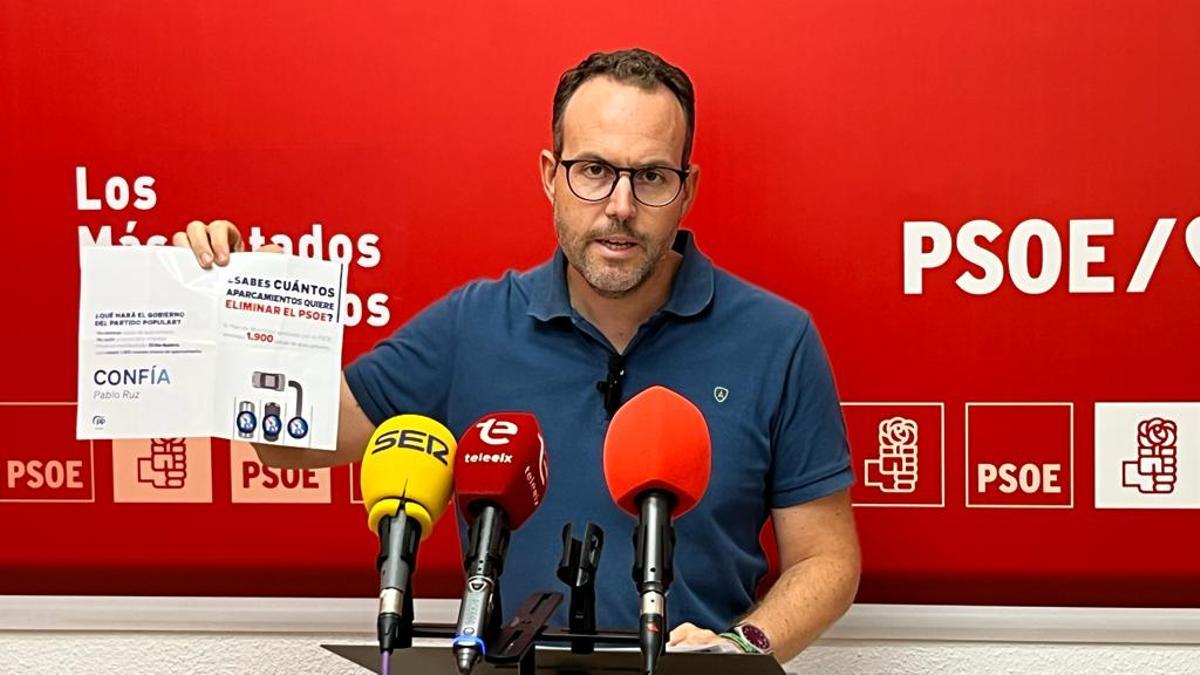 El portavoz del PSOE con un folleto del PP sobre el recorte de aparcamientos