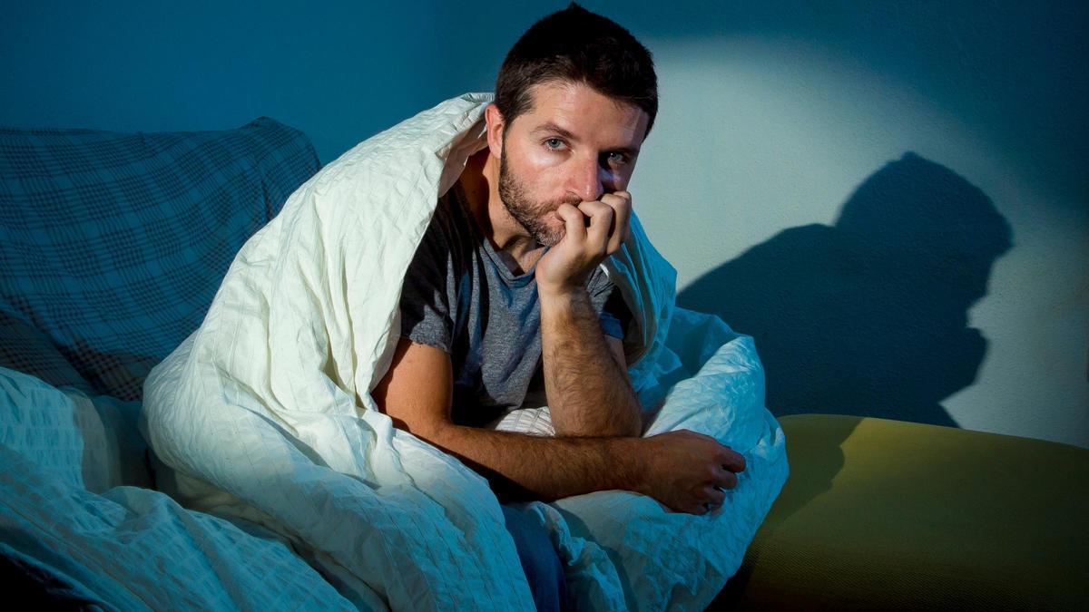 Un insomne sentado en la cama.