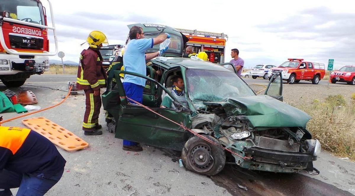 Bomberos y sanitarios atienden a un herido en un accidente de tráfico.