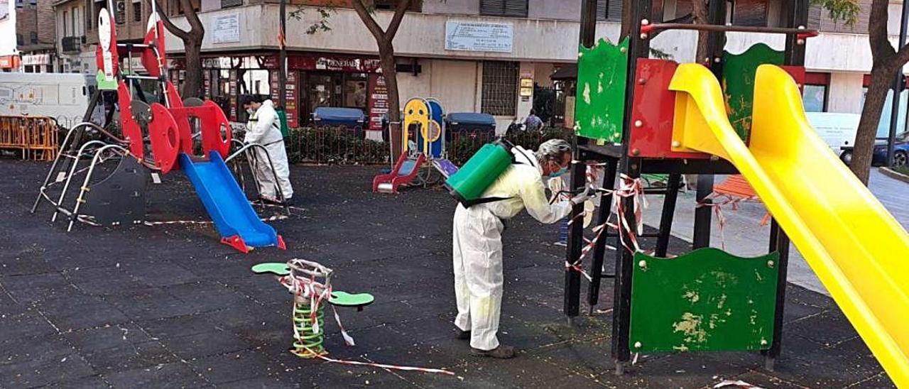 Unos operarios desinfectan un parque infantil durante la pandemia.