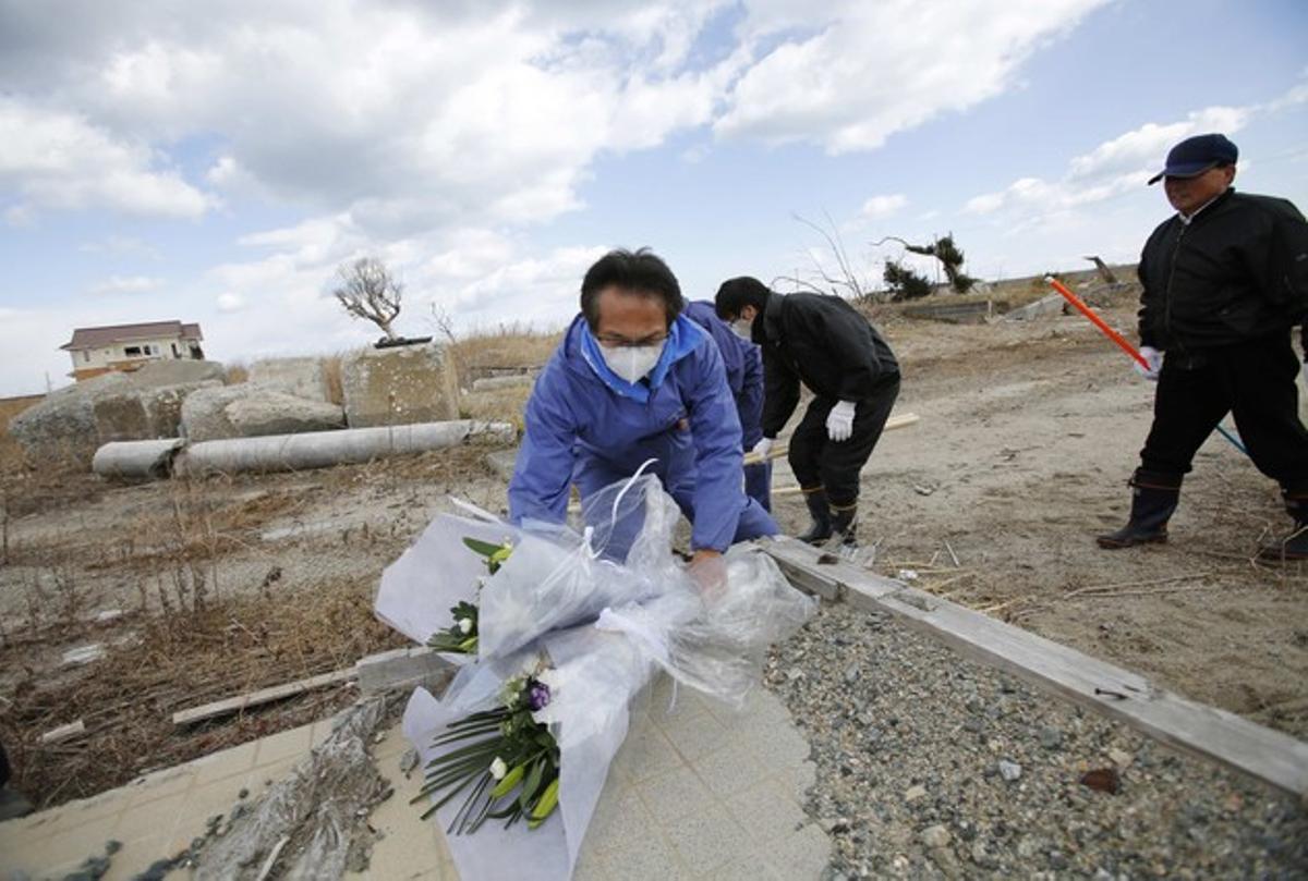 Un grup d’homes dipositen flors a Namie, a la prefectura de Fukushima.