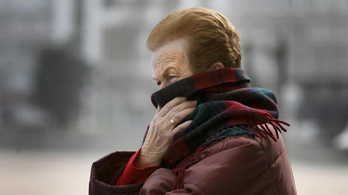 Una mujer se protege del frío en el paseo marítimo de A Coruña