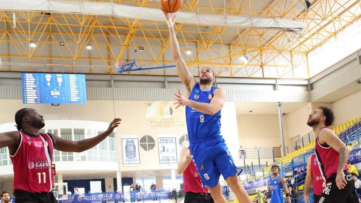 Iván Cruz, del Melilla, captura un rebote ante la mirada de Idehen y Webster