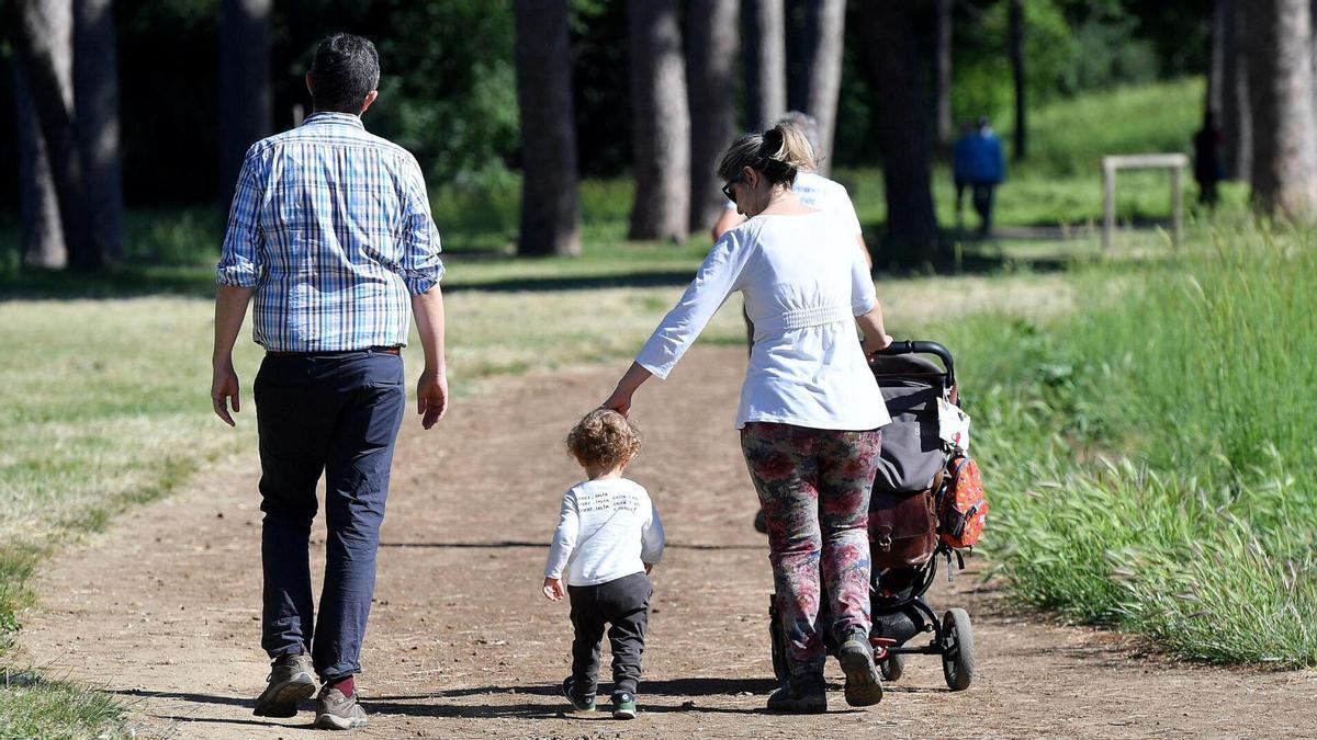 Una pareja pasea con su hija por el parque.