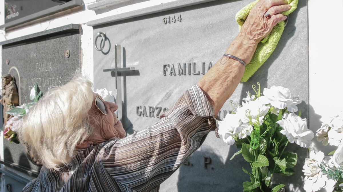 María Concepción González Cebrián, de 87 años, limpia el nicho familiar en el cementerio de Cáceres.