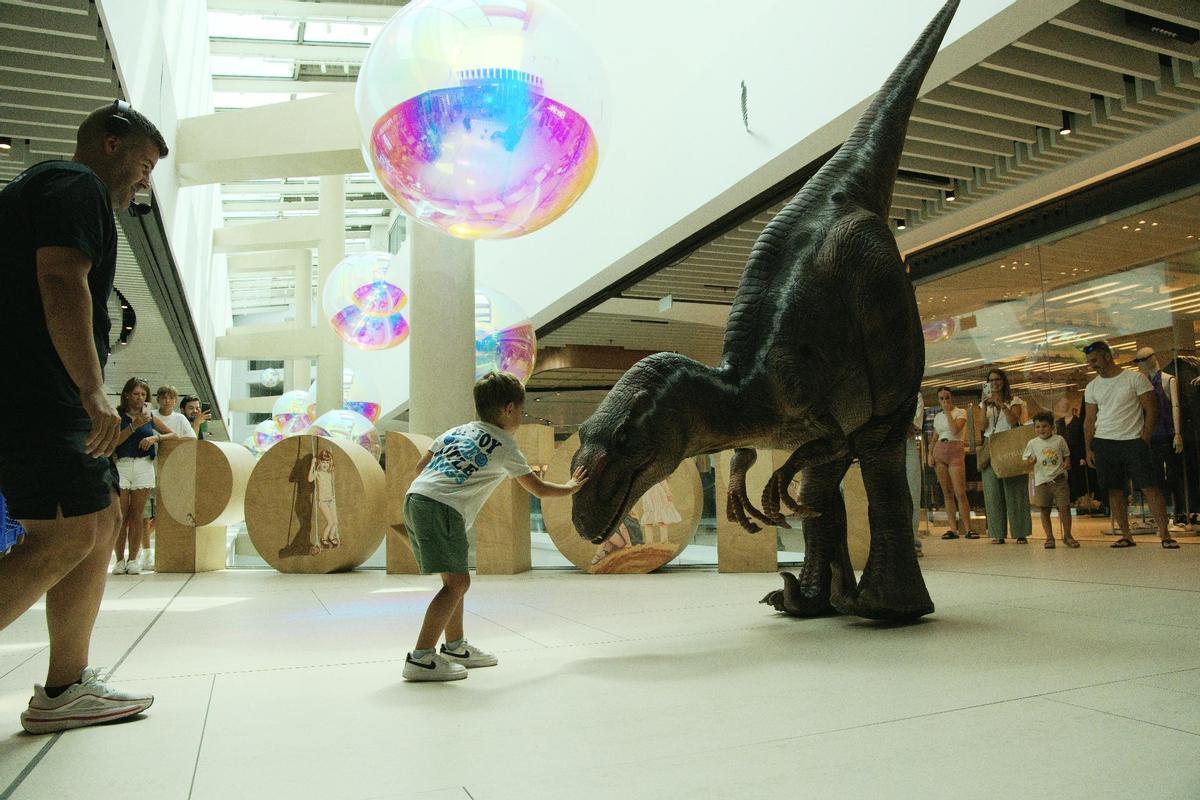Un niño acariciando a un T-Rex en Porto Pi