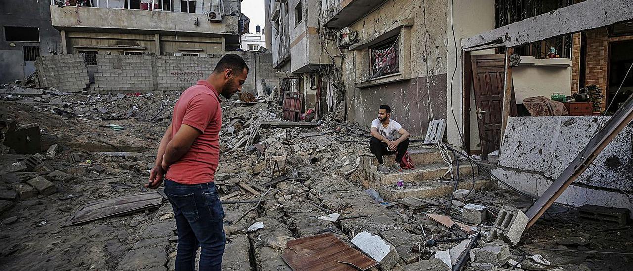 Varias personas miran los restos de su casa destruida por las bombas israelíes en Gaza.  | MOHAMED SABER/EFE