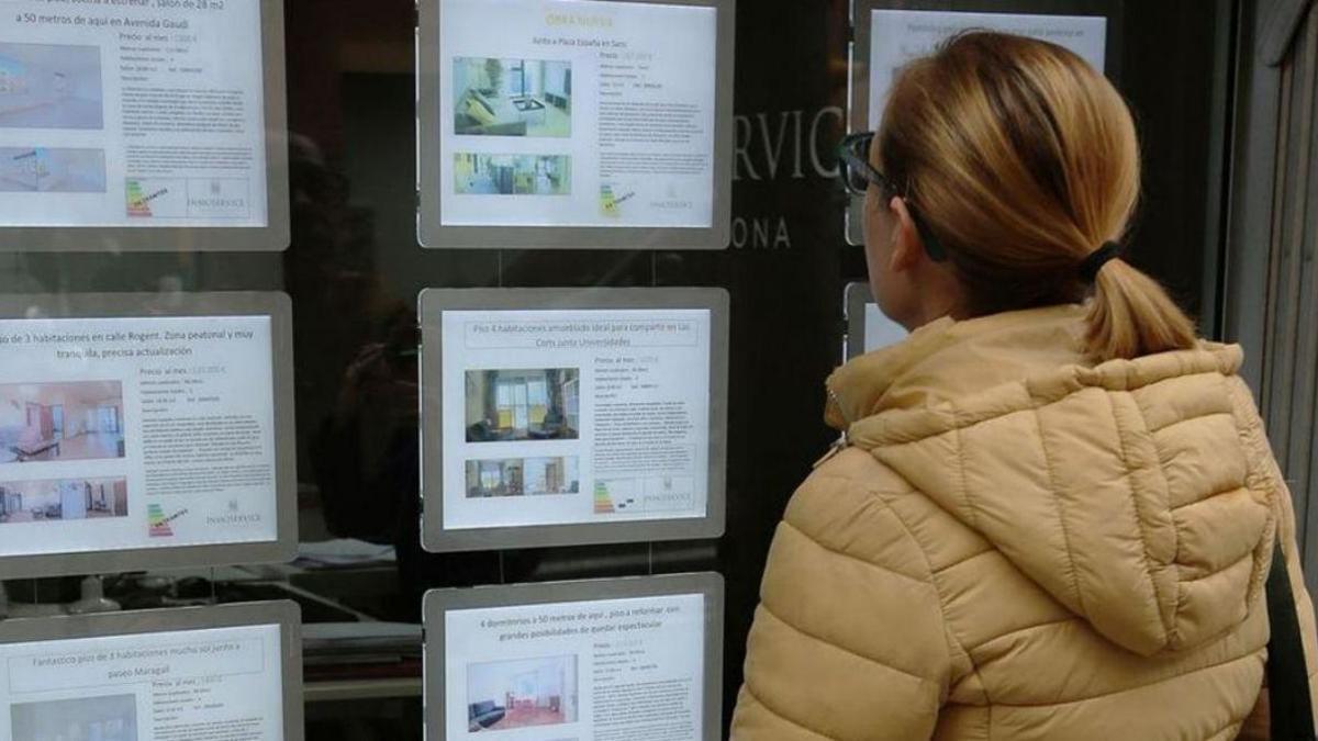 Una mujer observa los anuncios en el escaparate de una inmobiliaria. | L. O.