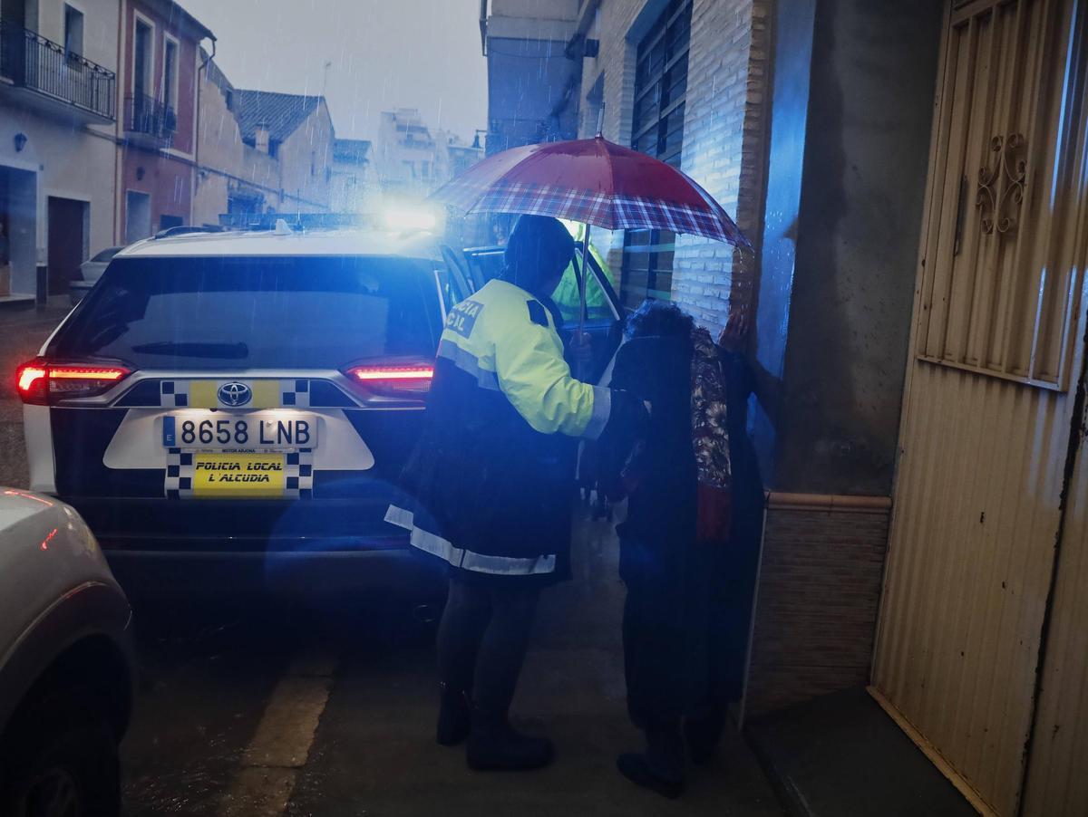 Agentes de la Policía Local de l'Alcúdia evacúan a una mujer con movilidad reducida de su vivienda, ante el riesgo de inundación.
