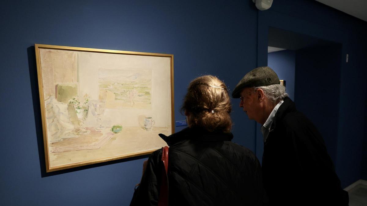 Pedro Serna y su mujer, Isabel González, contemplan uno de los cuadros de la exposición 'El acuarelista sentado'