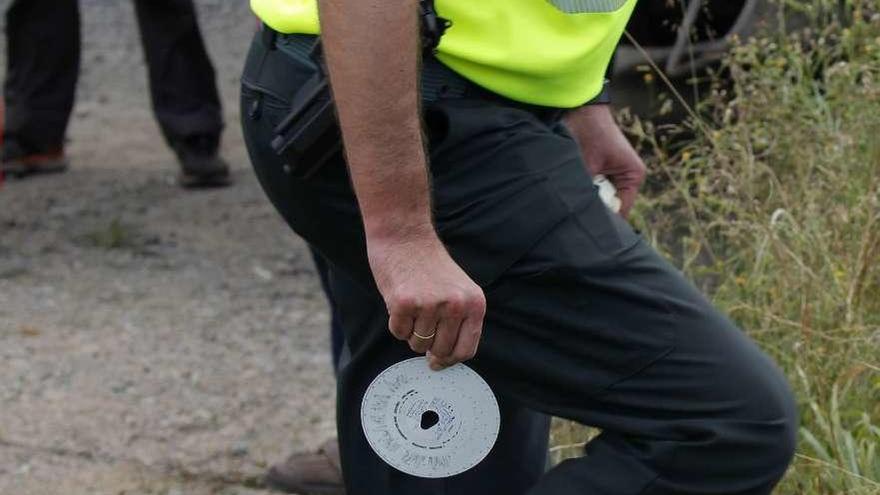 Un guardia civil abandona el lugar del accidente con un disco del tacógrafo en la mano.