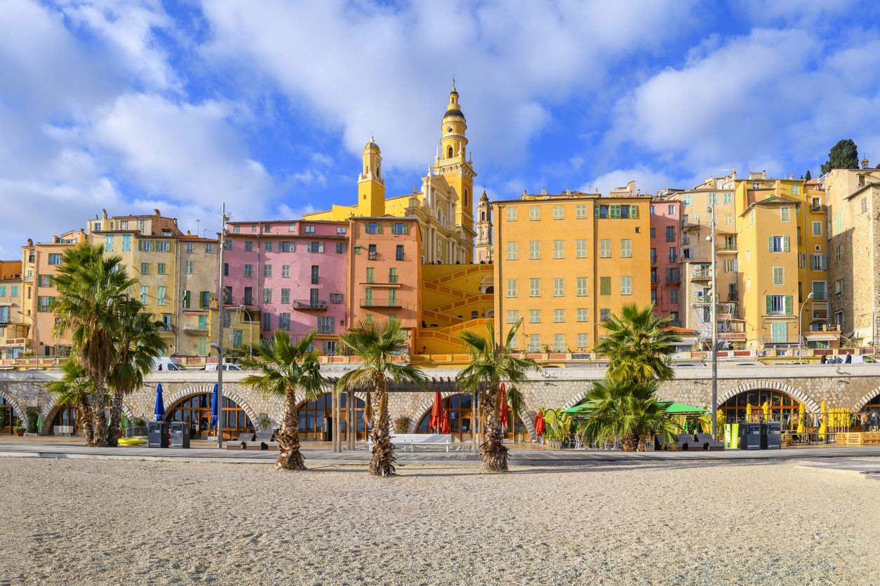 Vista desde la playa de Plage des Sablettes y el paseo marítimo del colorido casco antiguo de Menton, Francia.
