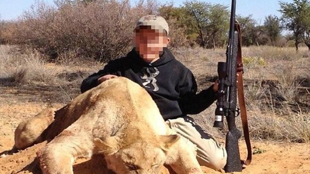 Un niño de siete años sostiene con la mano izquierda un rifle de casa y con la derecha acaricia el lomo del león que acaba de matar.