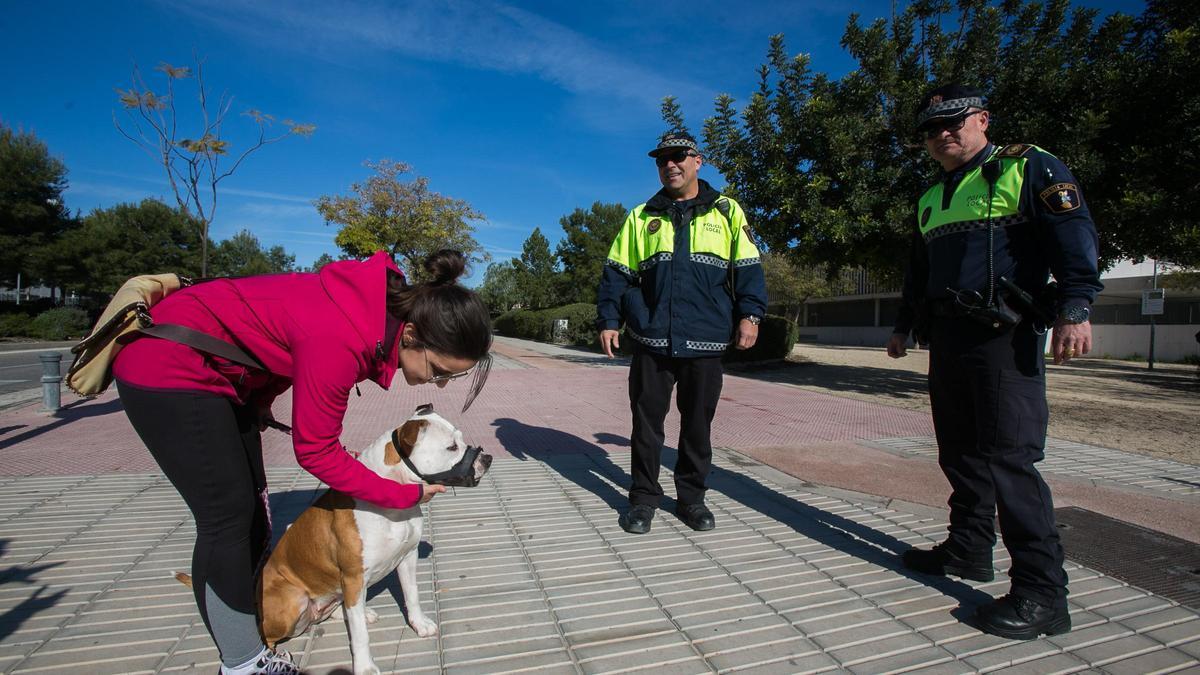 Dos agentes hablan con la dueña de un perro potencialmente peligroso que lleva bozal.