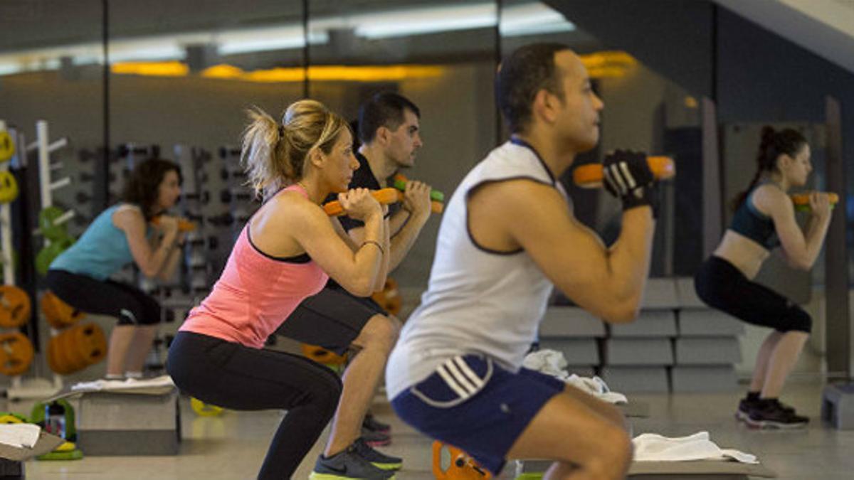 Varios usuarios de un gimnasio del centro de Barcelona se ponen en forma.