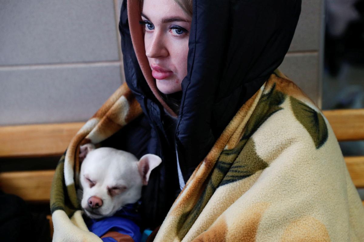 Una mujer que ha dejado Ucrania descansa junto a su perro en la estación húngara de Zahony.