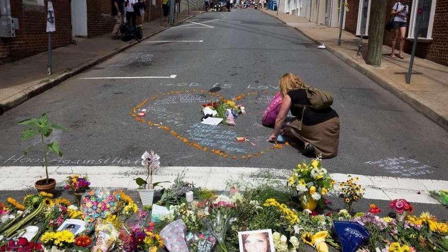 Una mujer coloca flores en el lugar donde la abogada Heather Heyer murió atropellada por un supremacista.