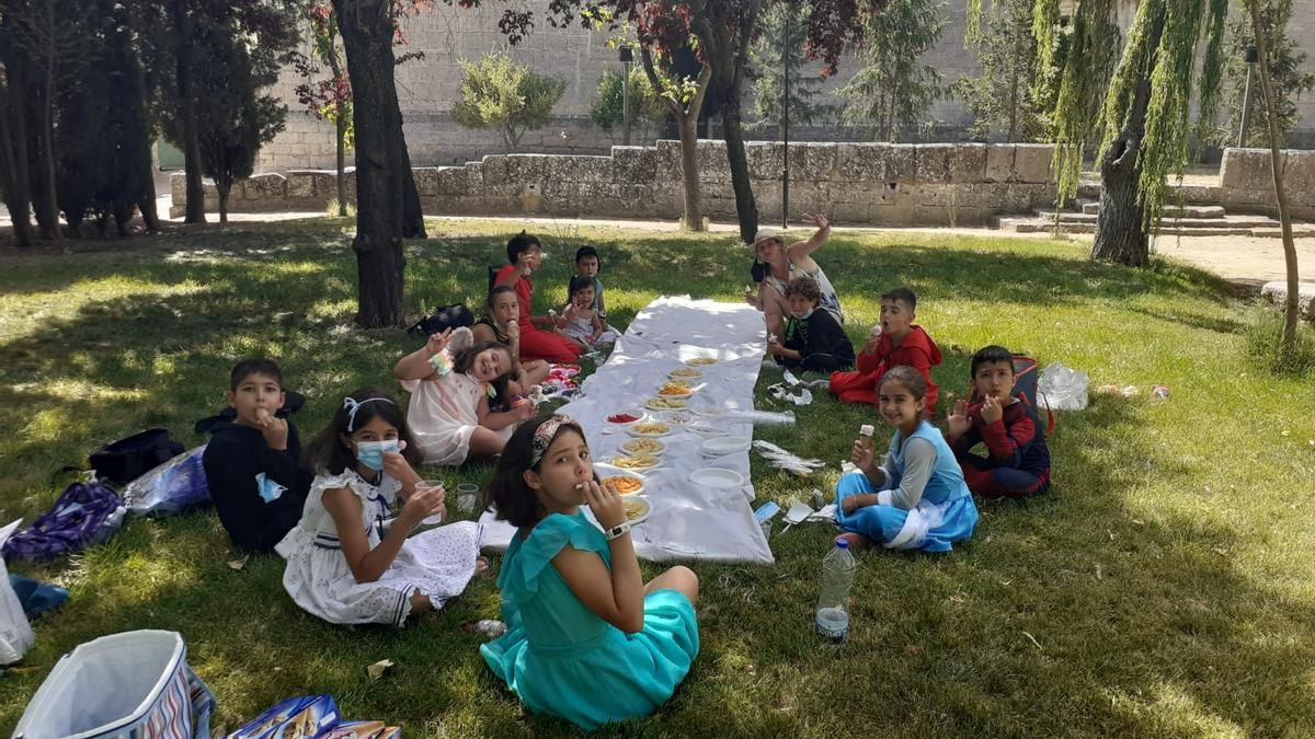 Los niños disfrutan de un almuerzo en una zona ajardinada de la localidad