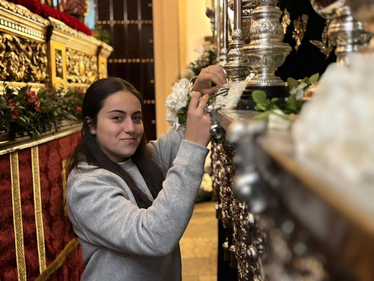 Carla Díaz coloca claveles blancos en el paso de la Virgen de los Dolores de Badajoz.