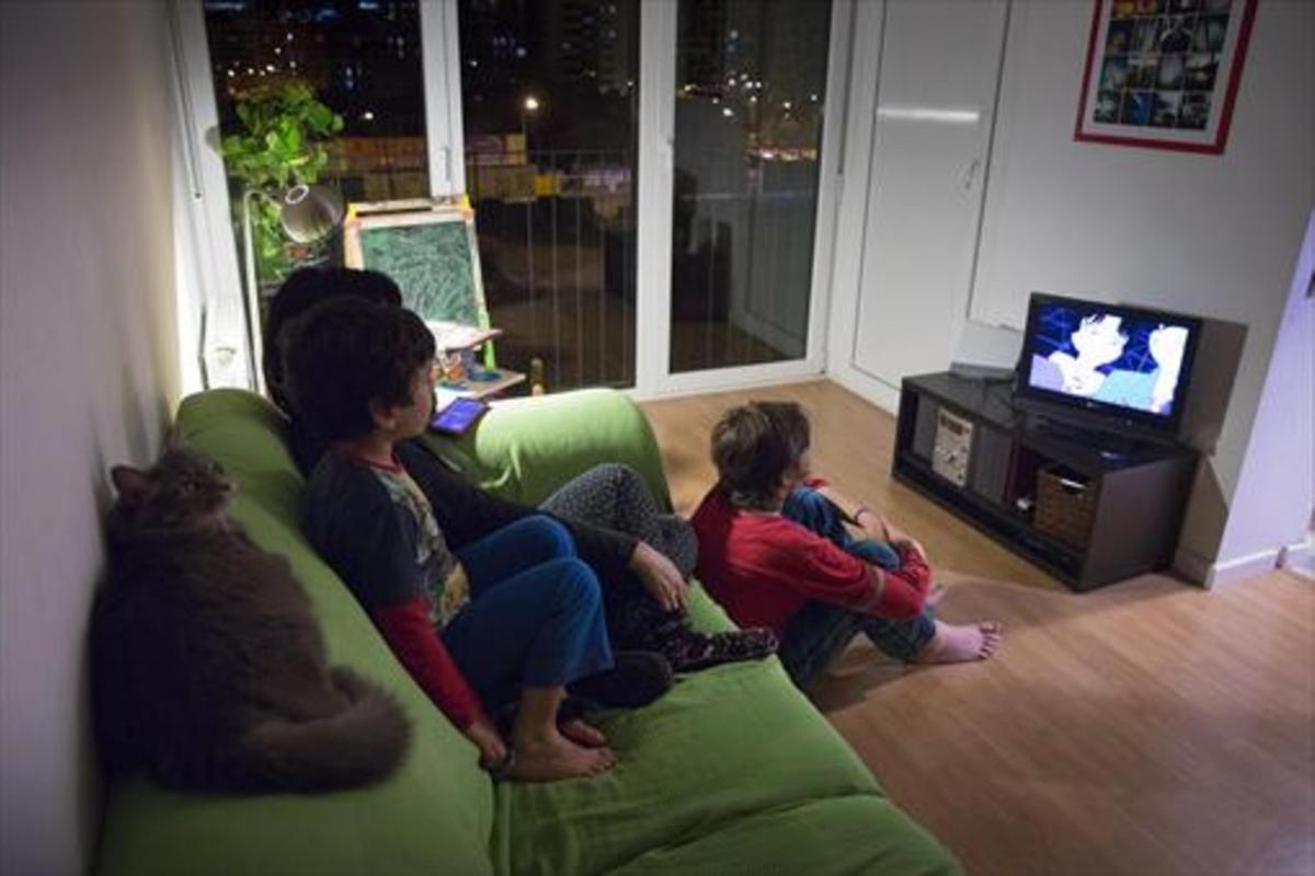 Tres niños miran un programa de dibujos animados.