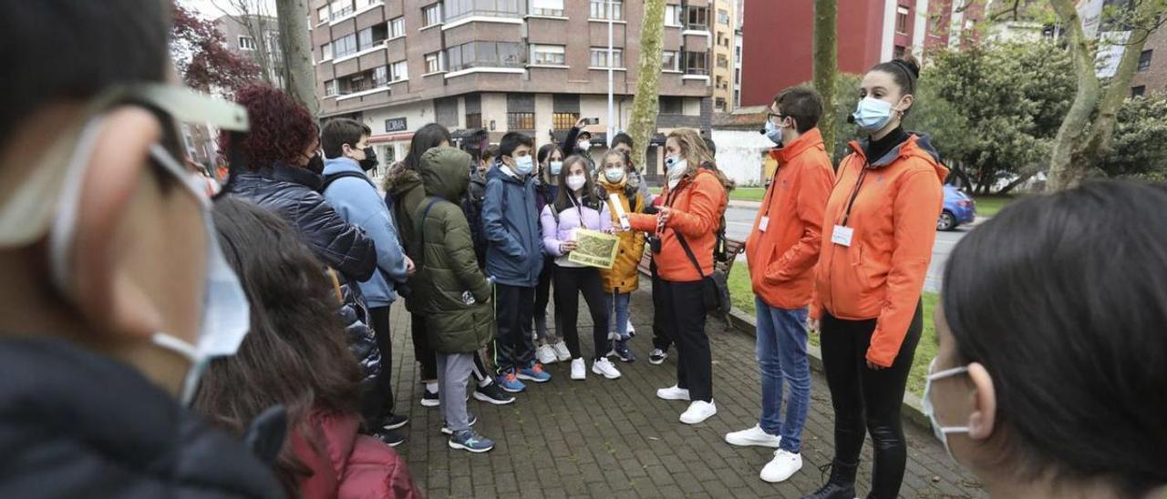 Una docente y dos estudiantes del Instituto La Magdalena, de naranja, explican a los alumnos de Las Vegas la ruta por Avilés en el parque del Carbayedo. | Ricardo Solís