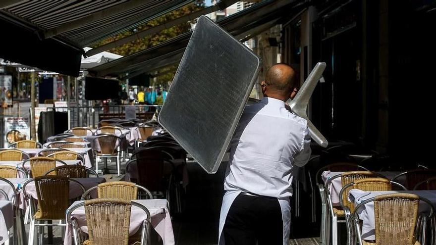 Un camarero recoge una mesa de una terraza de un restaurante.