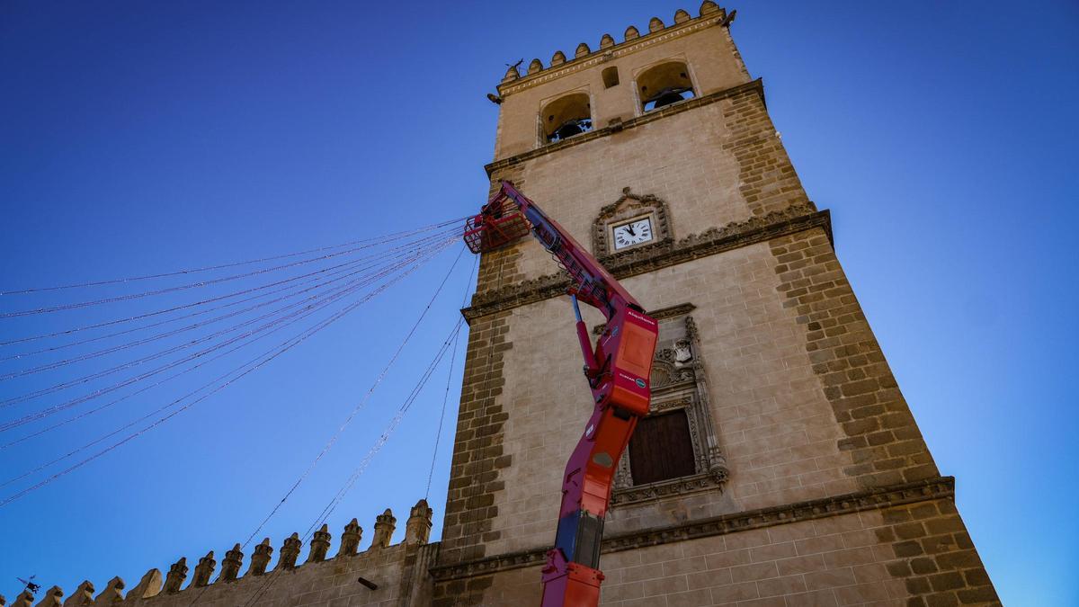Un operario trabaja en altura con una de las grúas junto a la torre de la catedral de Badajoz.