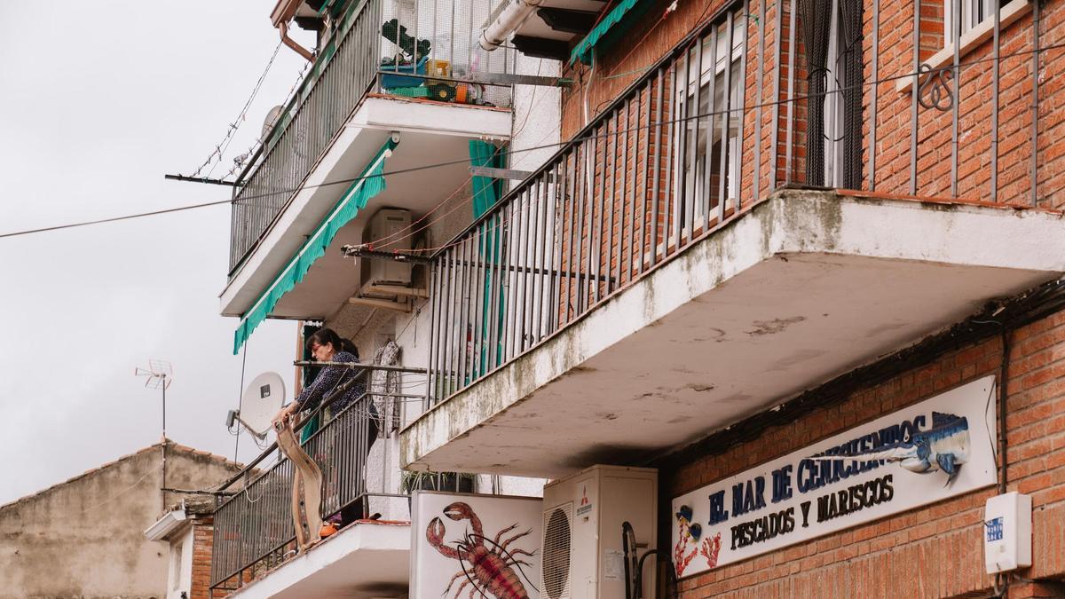 Una mujer limpia una alfombra en una calle del centro de Cenicientos.