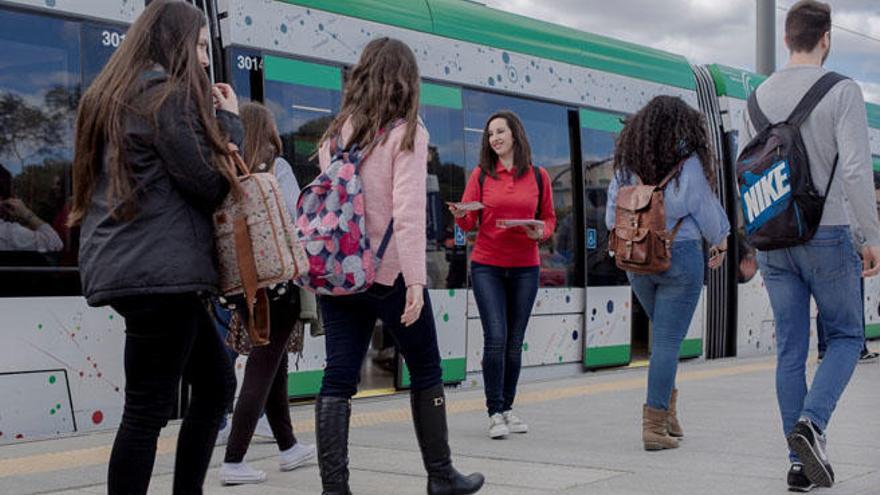 Una joven reparte folletos entre los jóvenes usuarios del metro.