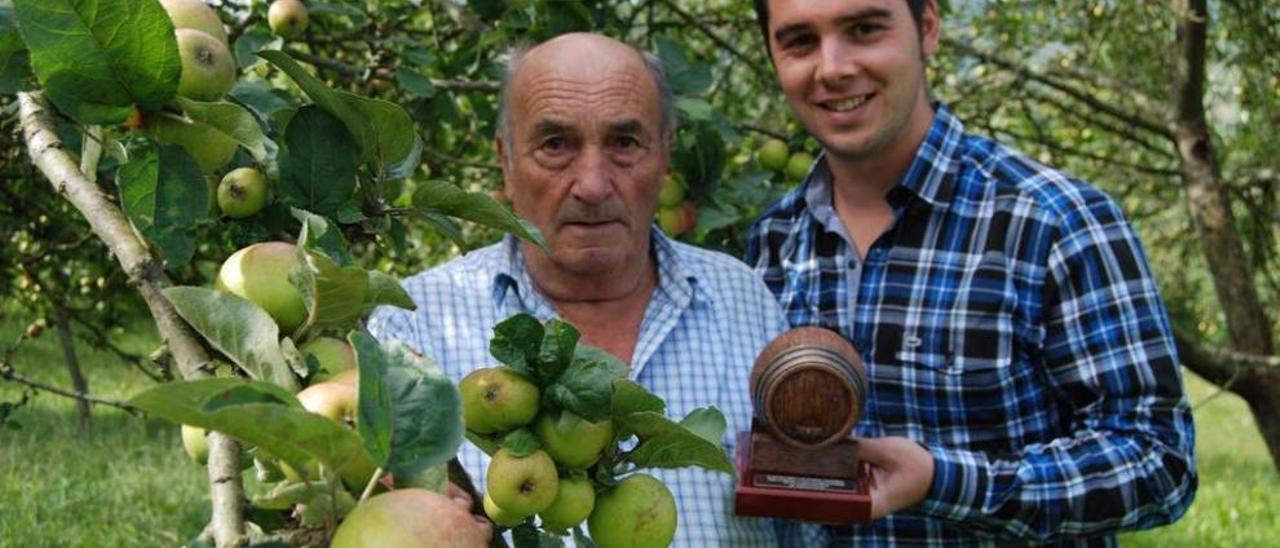 Germán Villar y su ahijado, en la pumarada de la familia, con el trofeo de la sidra ganadora.