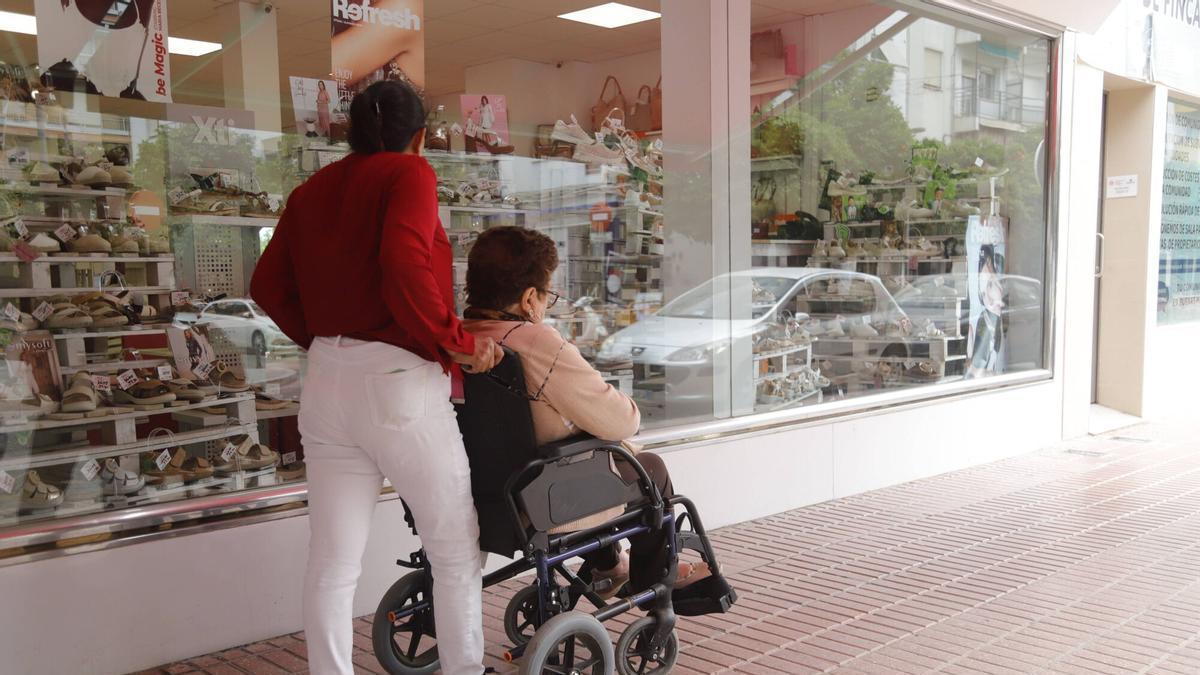 Una persona cuida de una mujer mayor.