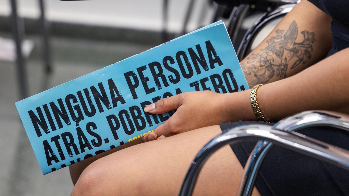 Una mujer sostiene una publicación de una organización de lucha contra la pobreza.
