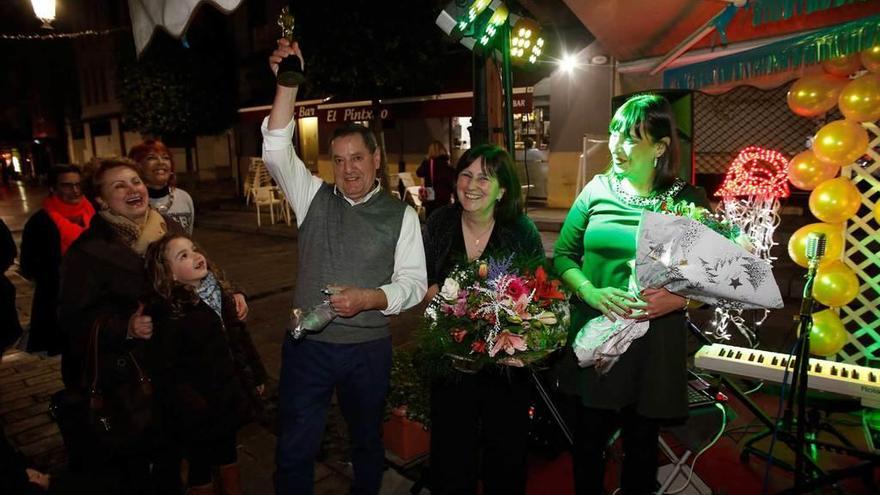 Alfredo Rodríguez levanta la estatuilla imitación del &quot;Oscar&quot; que le regalaron por ser el &quot;mejor barista&quot;, en compañía de su esposa, Rosabel Montiel, y la camarera Begoña Redondo, ambas con ramos de flores.