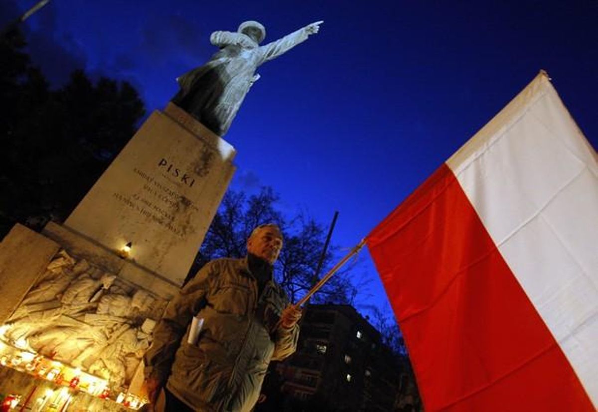 A man holds a Polish flag in Budapest, during a candlelight commemoration for the victims of an air crac in Russia