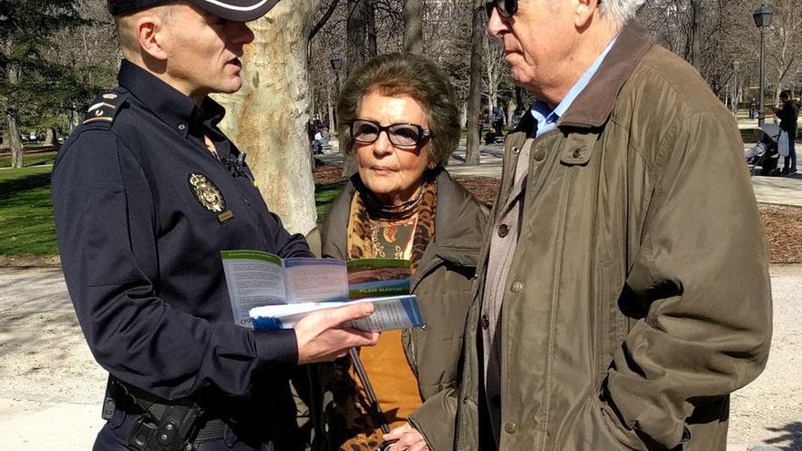 Un agente de la Policía Nacional dialoga con una pareja personas mayores.