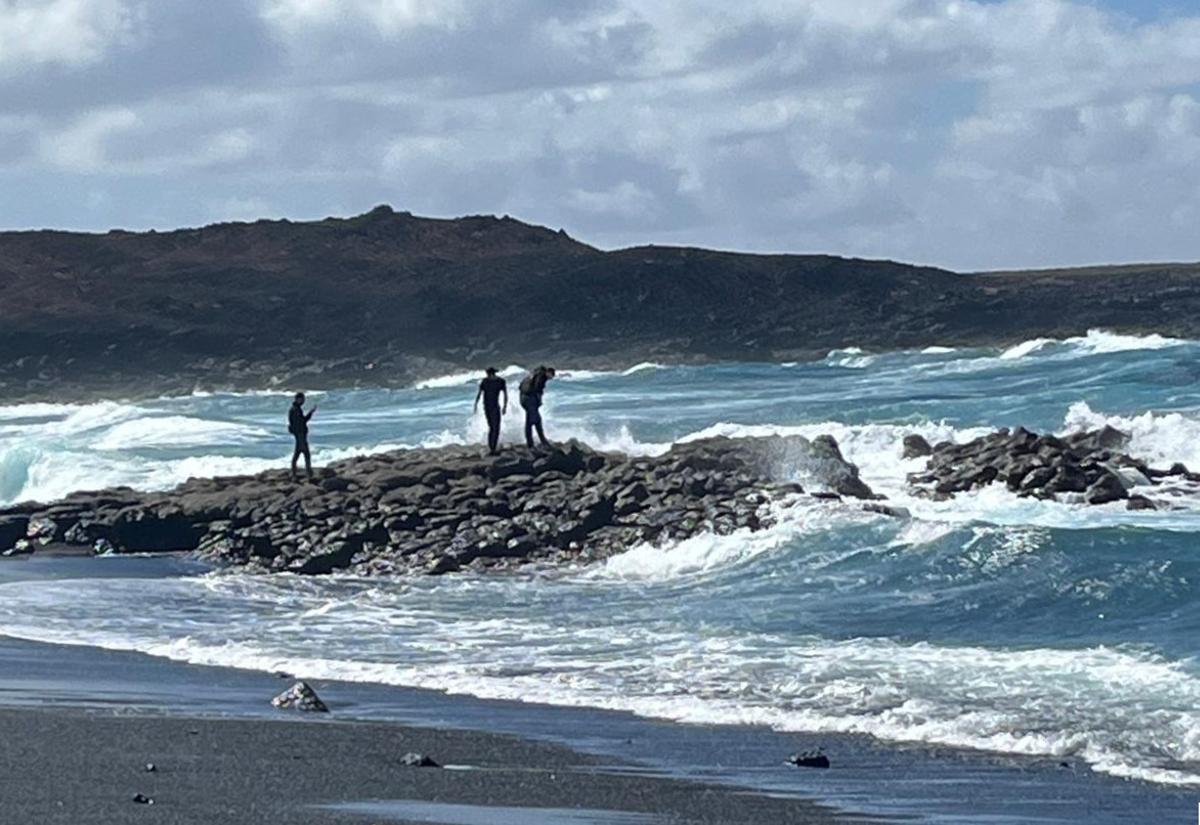 Varias personas este domingo, 22 de marzo, ante el oleaje en la playa de Janubio, en el sur de Lanzarote, pese al mal tiempo por la borrasca Therese