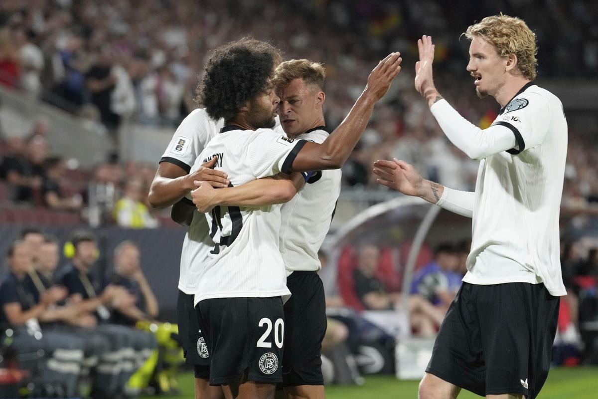 Germany's Serge Gnabry, left, celebrates with teammates Nick Woltemade, right, and Joshua Kimmich , center, after scoring the opening goal during the FIFA World Cup Group A qualifying soccer match between Germany and Northern Ireland at RheinEnergieStadion stadium in Cologne, Germany, Sunday, Sept. 7, 2025 (AP Photo/Martin Meissner)