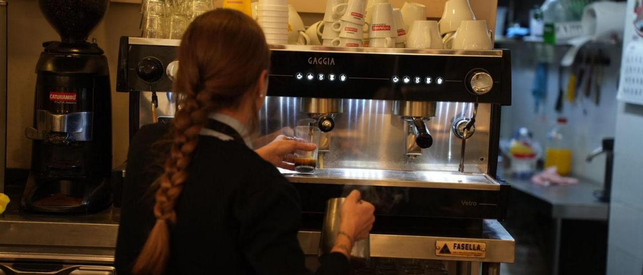 Una trabajadora prepara un café en un bar.