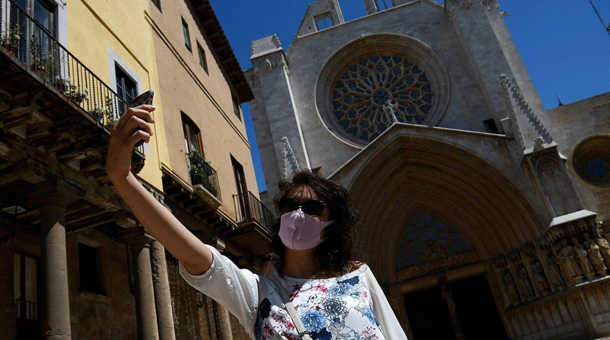 Una mujer con mascarilla se hace un selfi ante la catedral de Tarragona, el 11 de mayo.
