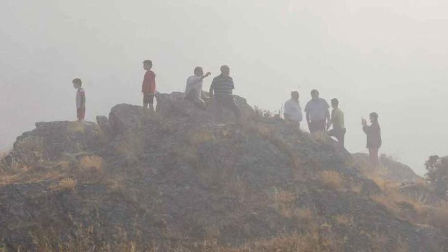 Curiosos apostados en los peñascos de Los Infiernos entre una nube de humo.